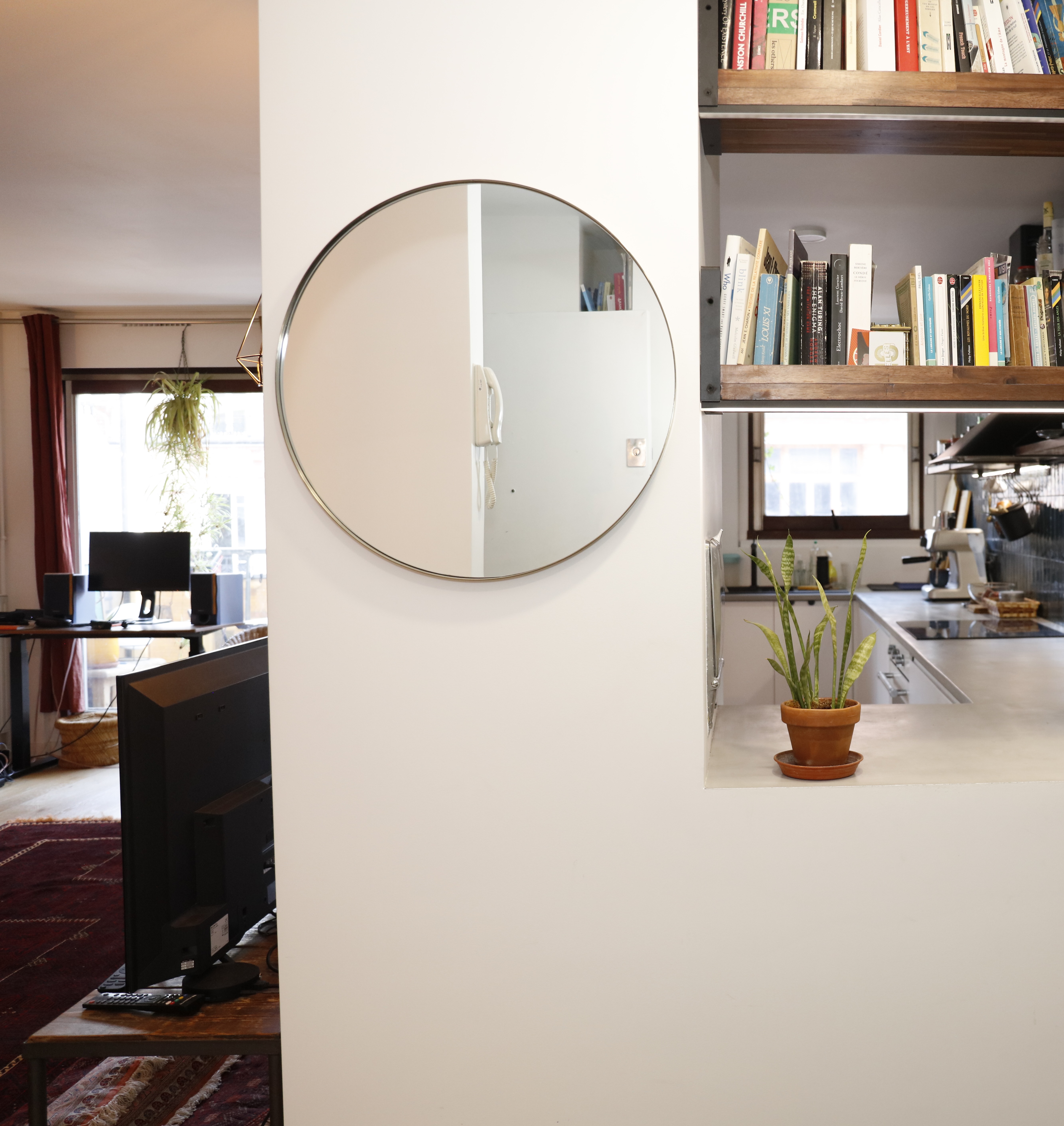 Modern kitchen with round mirror, built-in bookshelves, and workspace view